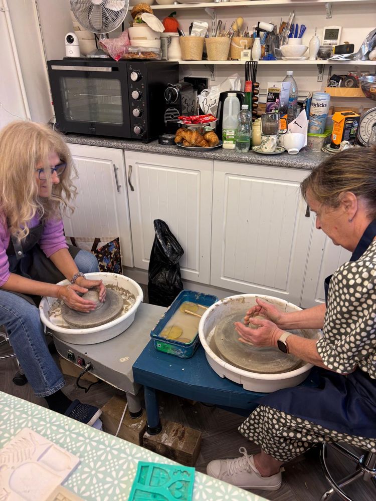 Two people side by side at potter's wheels