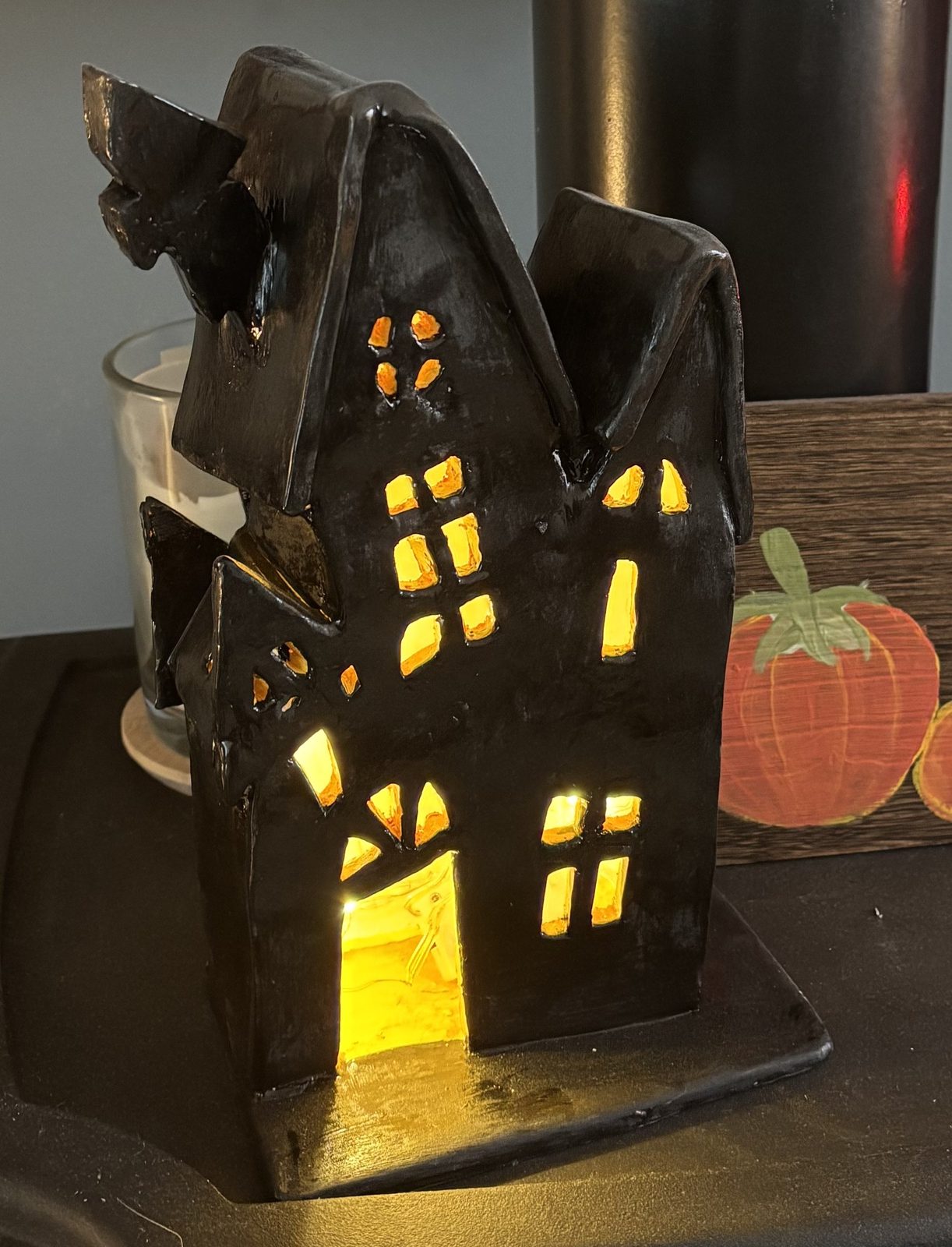 A glowing clay tea light house, lit from within