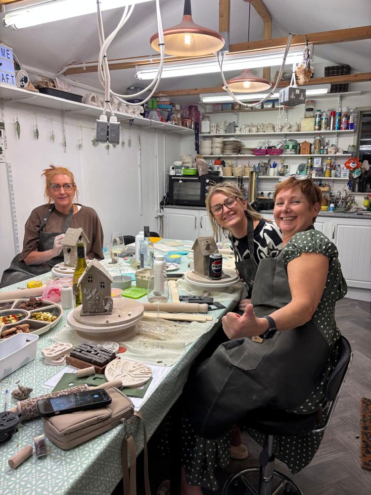 Three makers at the big table, one giving a thumbs up
