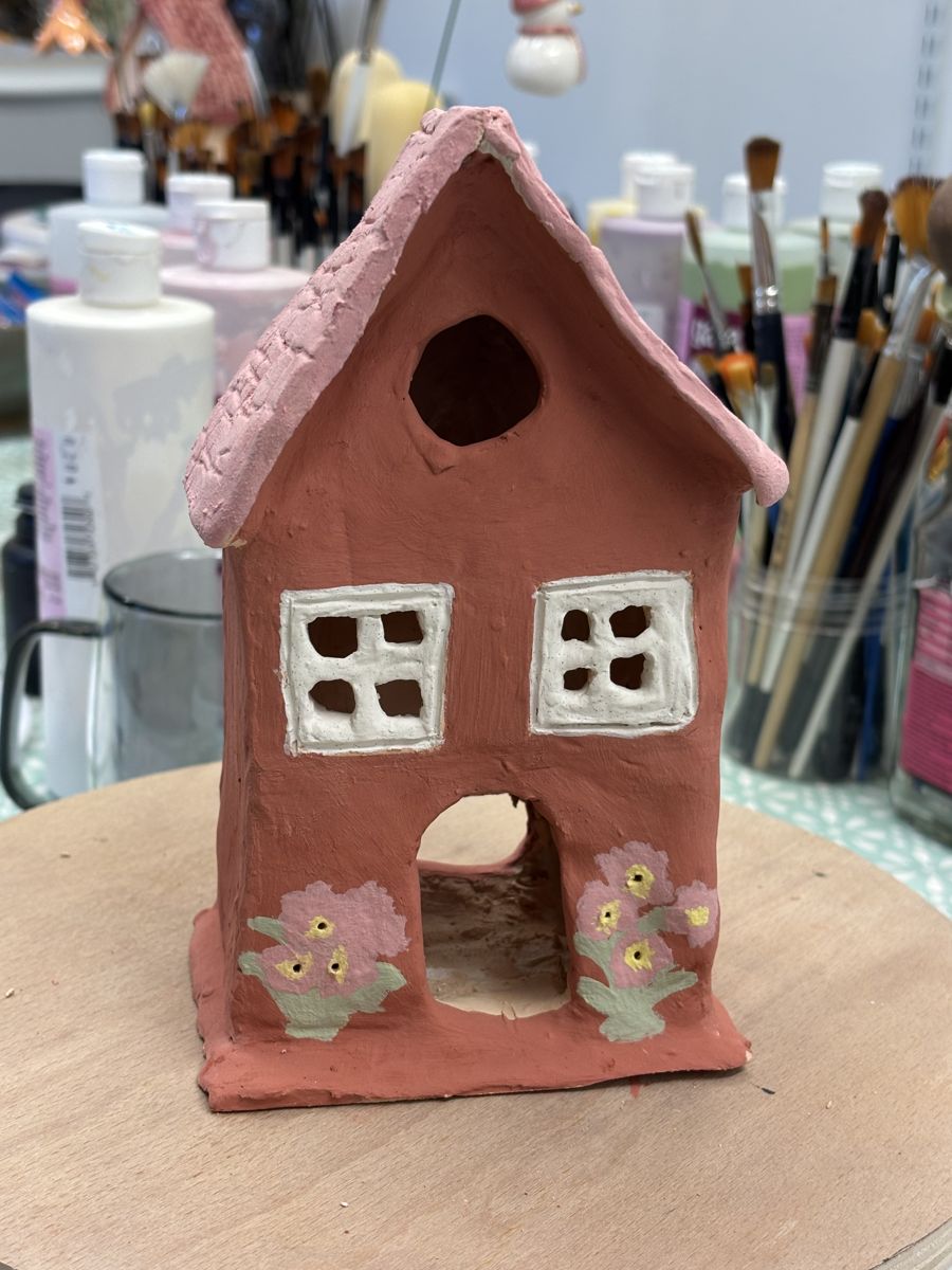 Bisque fired clay house painted terracotta with white windows and flowers