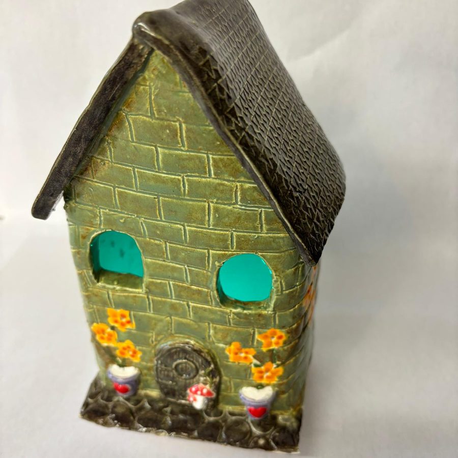Green glazed clay house with a brick texture and flowers