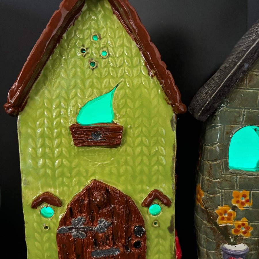 Tall green clay house with a carved wooden-look door