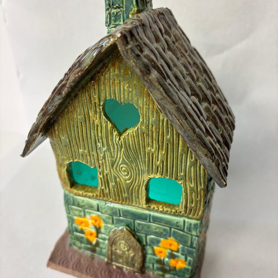 Glazed clay house with a heart window and flowers