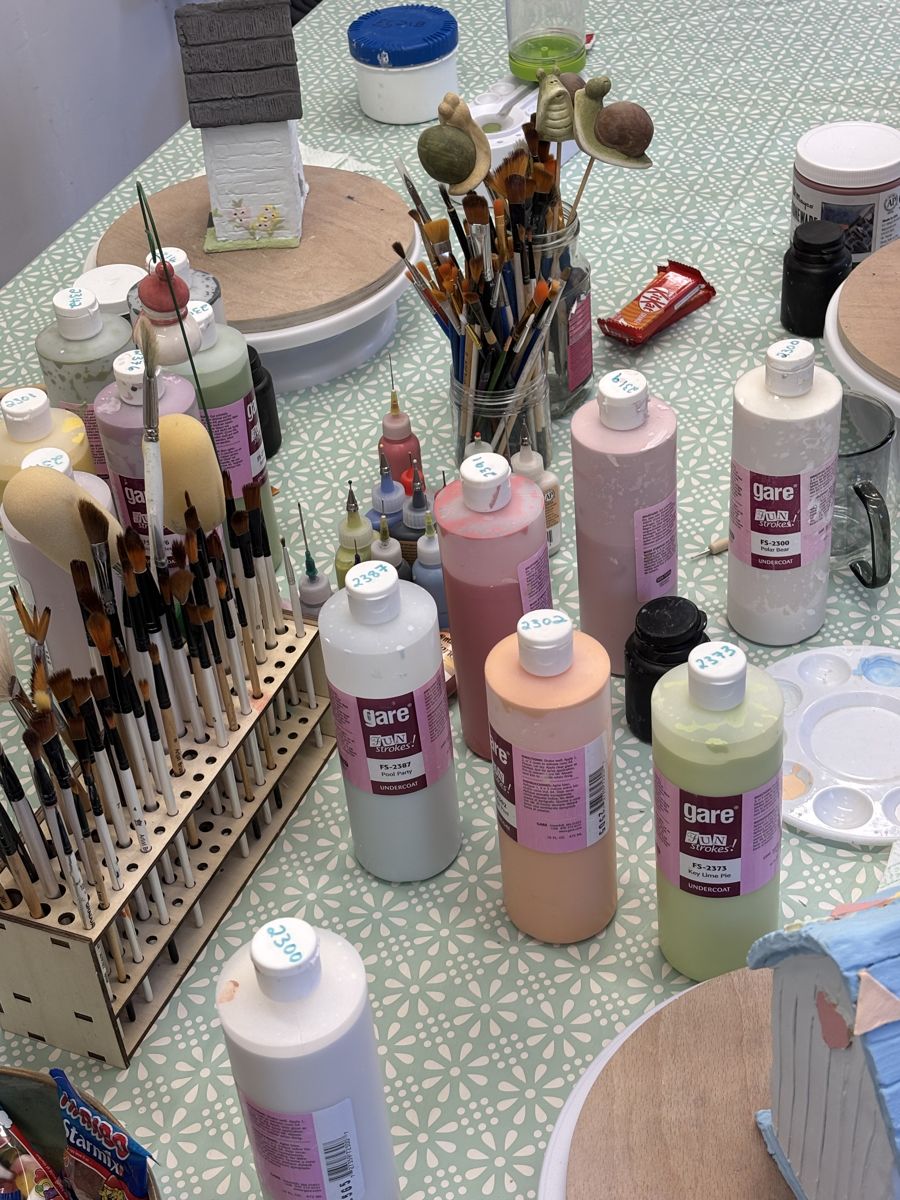 Brushes and bottles of glaze laid out on the studio table