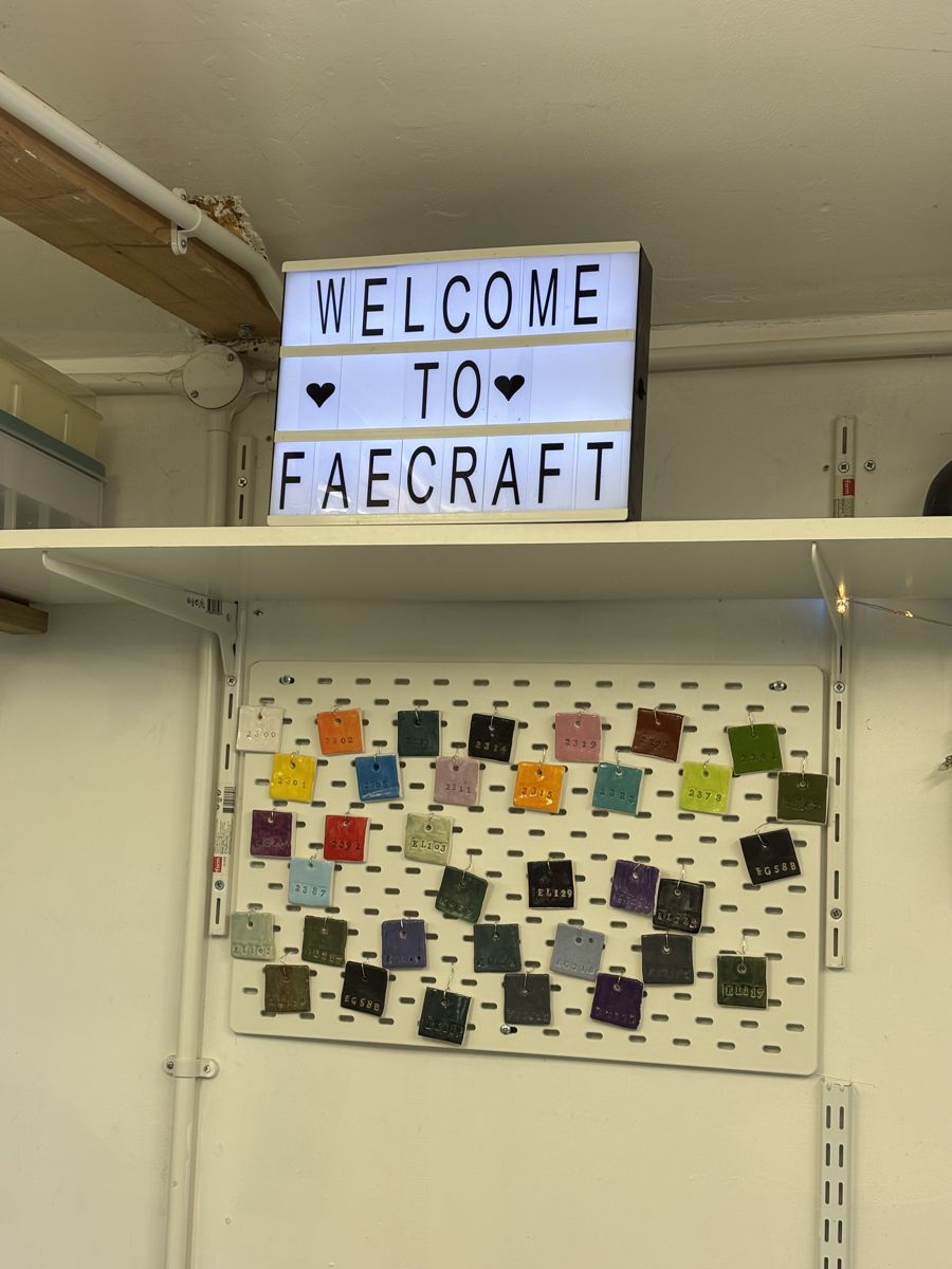 Welcome to FaeCraft light box sign above a board of glaze test tiles