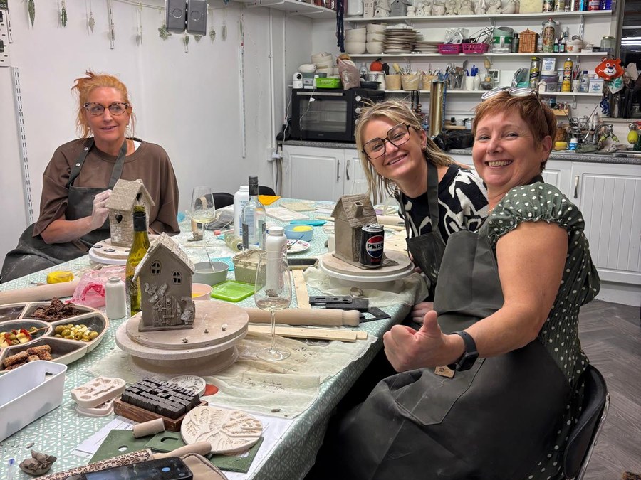 Three makers at the table with their clay houses