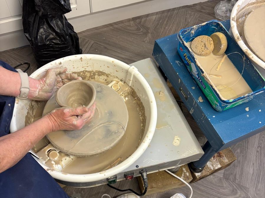 Hands opening out a bowl on the pottery wheel