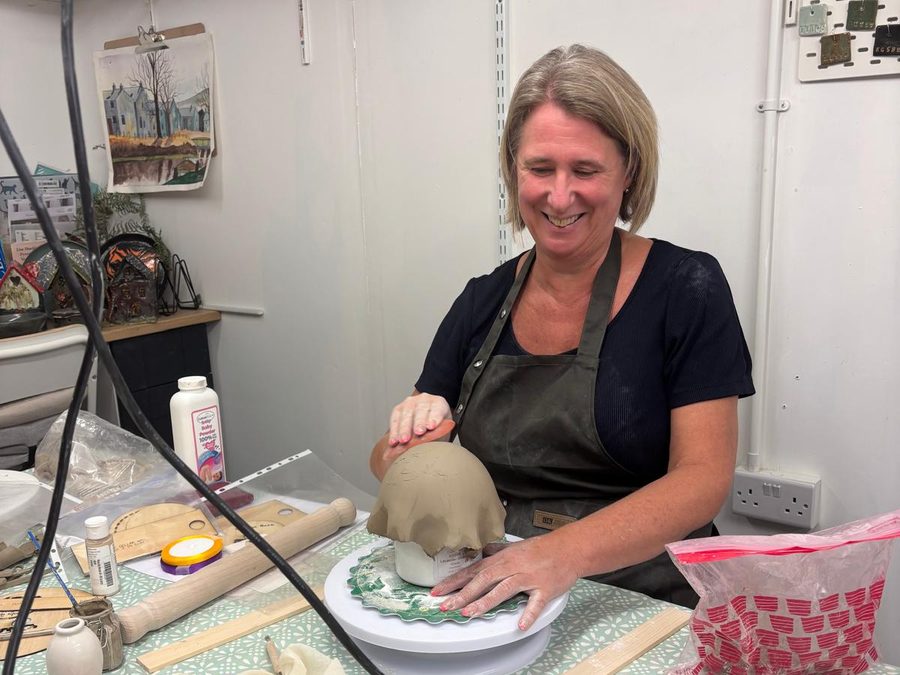 Shaping a clay bowl over a hump mould on a banding wheel